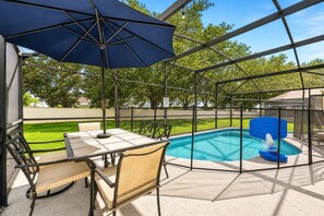 A covered outdoor area with a pool, a table, and chairs. - Heated Pool~Windsor Resort~Near Disney~Game Room (Kissimmee)