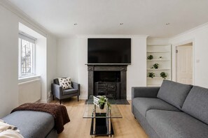 Een moderne woonkamer met een open haard, een bank, een fauteuil en een salontafel.