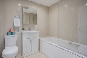 Een moderne badkamer met toilet, wastafel en bad.