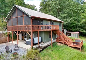 Ein zweigeschossiges Haus mit einer Veranda, einer Treppe und Sitzgelegenheiten im Freien.