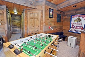 A room with a foosball table, a door, and a poster on the wall. - Work Hard Play Hard- View-Gameroom (Blue Ridge)