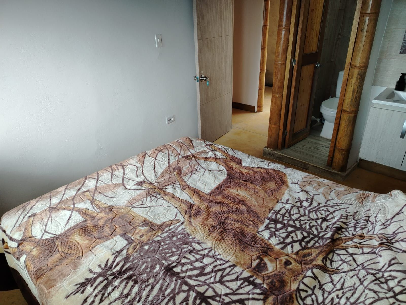 Een slaapkamer met een bed, een garderobe en een badkamer die door een open deur zichtbaar is.