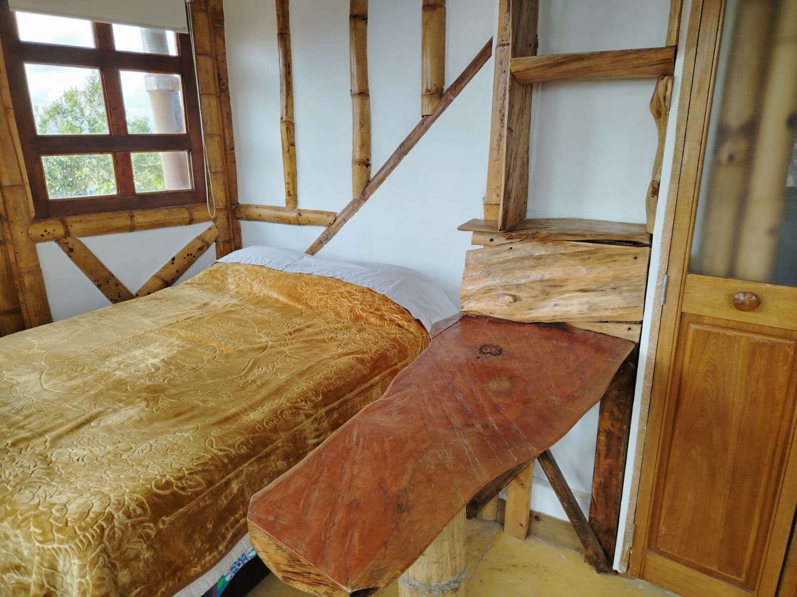Una cama con colcha estampada, un banco de madera y un cabecero de madera.