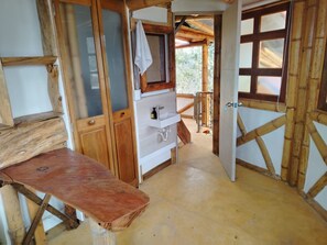 A rustic wooden interior with a bench, a sink, and a door leading to an outdoor area.
