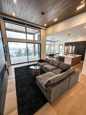 Una sala de estar moderna con un sofá modular, una alfombra negra y una mesa de centro de vidrio.