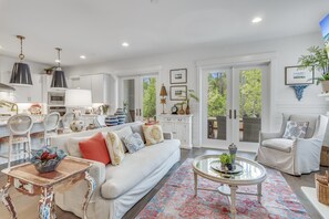 A spacious living room with a white sofa, a coffee table, and a dining area with white cabinetry and a kitchen in the background. - Beachy Keen 30A (Santa Rosa Beach)