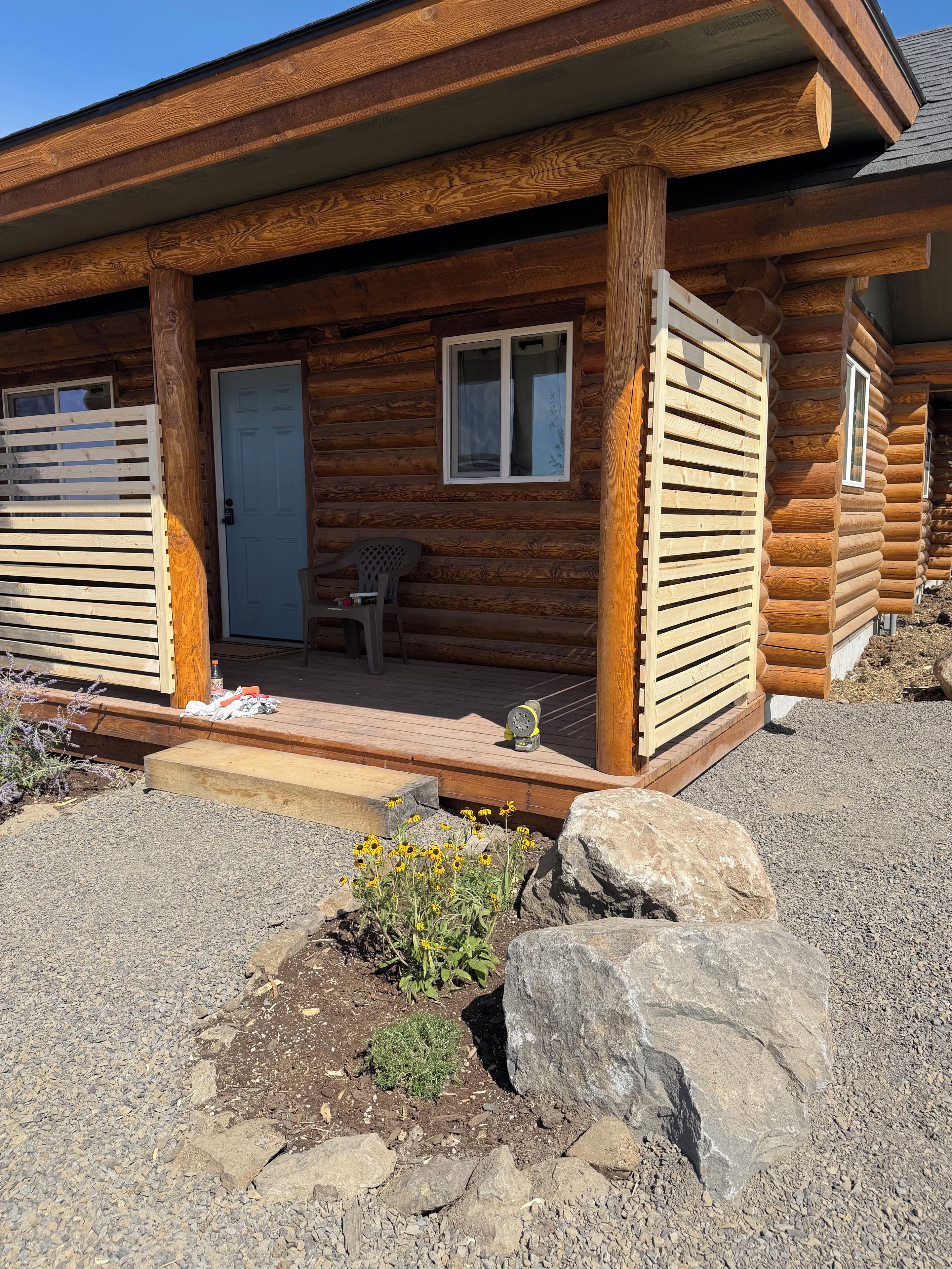 A log cabin with a porch, a door, and a window.