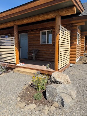 A log cabin with a porch, a door, and a window.