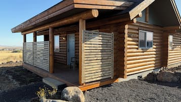 A log cabin with a porch, a door, and windows.