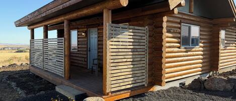 A log cabin with a porch, a door, and windows.