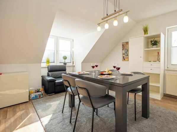 A dining area with a table, chairs, and a ceiling light fixture. - Apartment 16 on the 2nd Floor of Haus Stranddistel (Zingst)