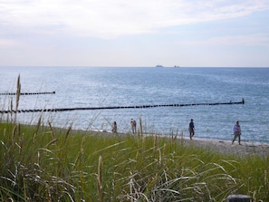 A beach with a breakwater extending into the sea, a few people on the shore, and a ship in the distance. - Apartment 16 on the 2nd Floor of Haus Stranddistel (Zingst)