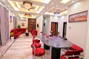 A conference room with a large oval table, red upholstered chairs, and a chandelier.