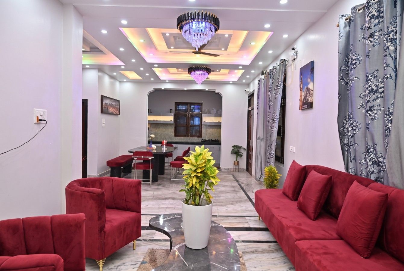 Una sala de estar moderna con sofás rojos, una planta en maceta en el centro y un área de comedor al fondo.