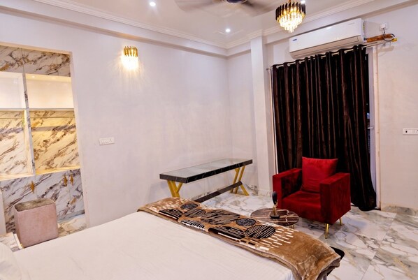 A bedroom with a bed, a red chair, a console table, and a marble wall.