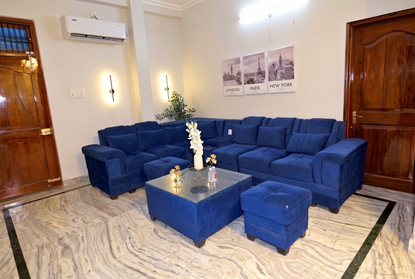 A living room with a sectional sofa, a glass coffee table, and a marble floor.