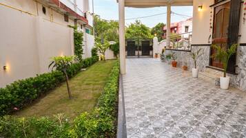 A covered outdoor area with a patterned floor, potted plants, and a gated entrance.