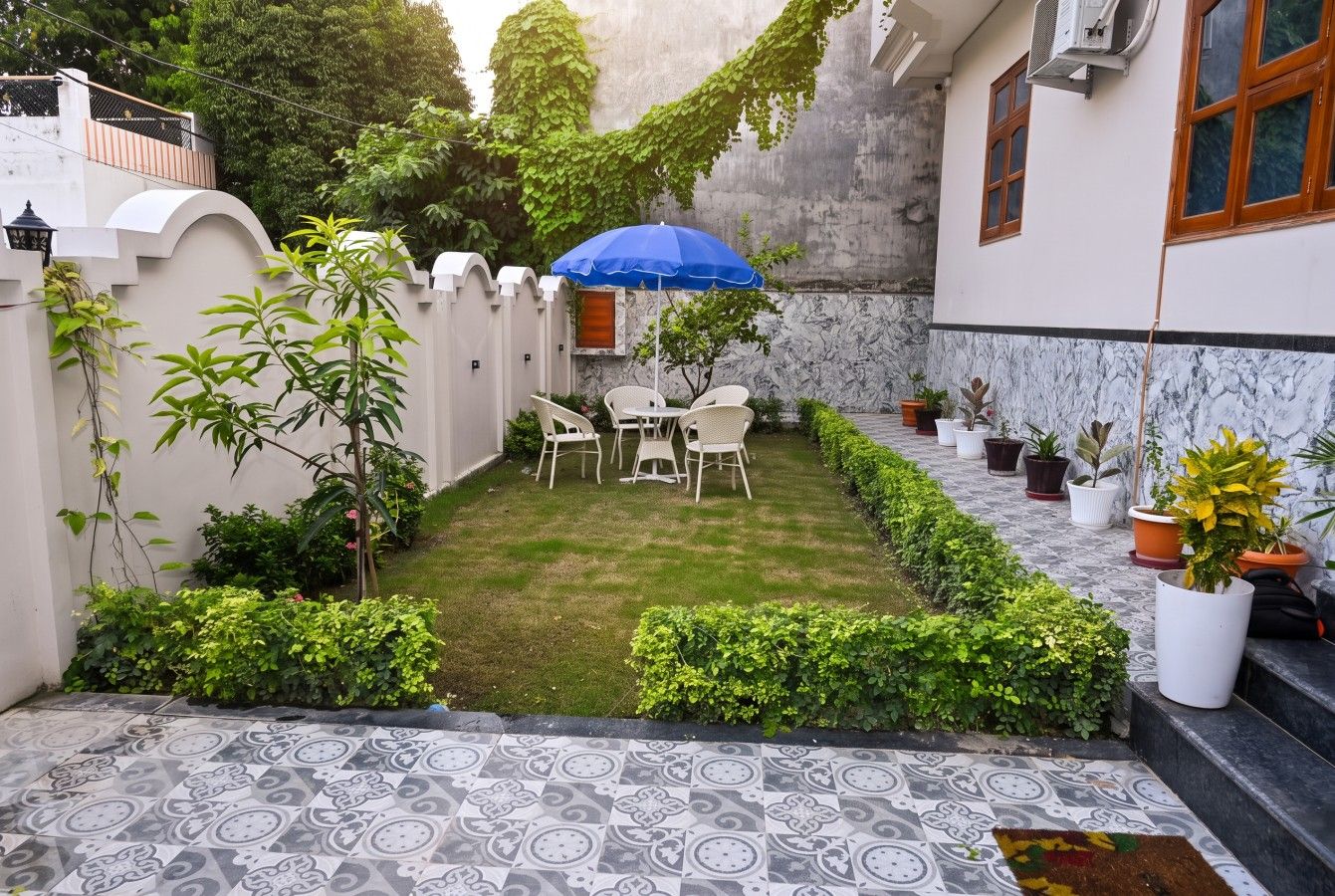 Un patio con zona de estar, plantas en macetas y suelo estampado.