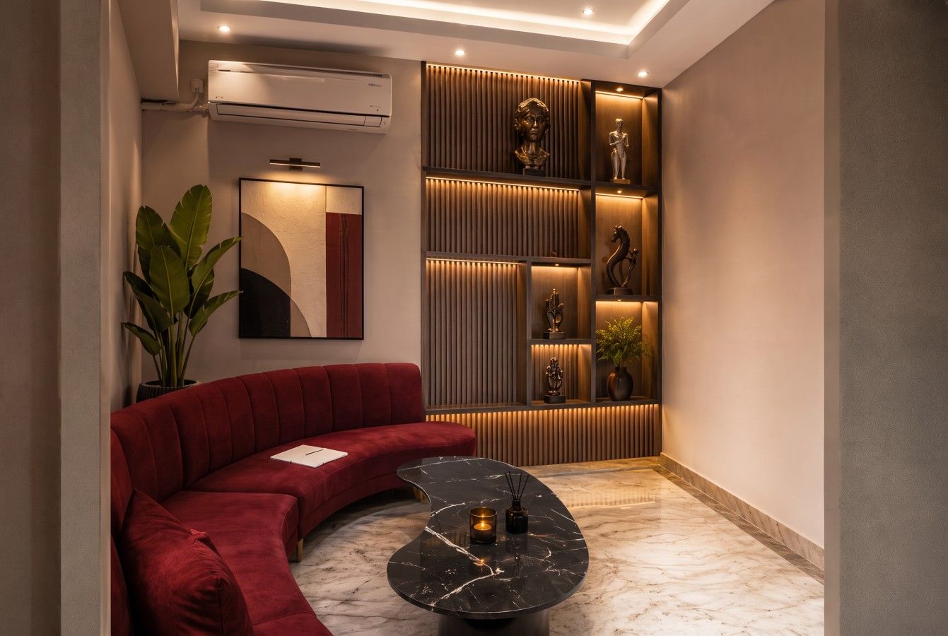 Een moderne woonkamer met een rode bank, een gebogen zwart bijzettafeltje en een wand met decoratieve objecten.