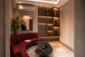 A modern living room with a red sofa, a curved black coffee table, and a wall with decorative items.
