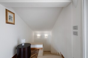 A narrow hallway with a wooden floor, a black trash bin, and a framed picture on the wall. - Apartment 'Casa Mimosa' with Private Terrace, Private Garden and Wi-Fi (Camaiore)