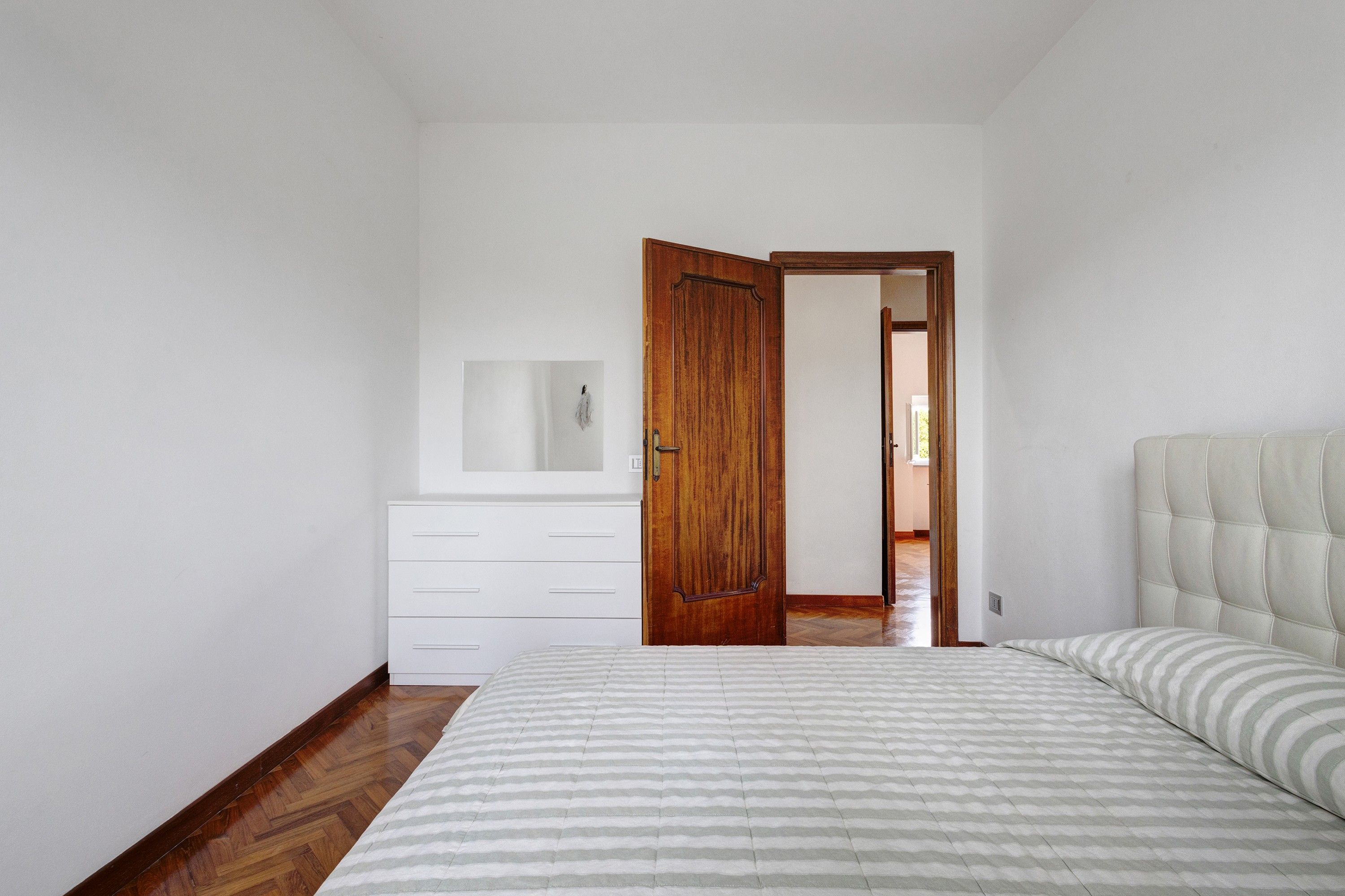 Un dormitorio con una cama, un aparador y una puerta de madera.