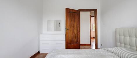 Une chambre à coucher avec un lit, une commode et une porte en bois.