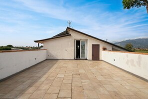 A rooftop terrace with a single door, a small window, and a view of distant mountains. - Apartment 'Casa Mimosa' with Private Terrace, Private Garden and Wi-Fi (Camaiore)
