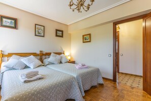 A hotel room with two beds, a wooden headboard, a chandelier, and framed artwork on the walls.