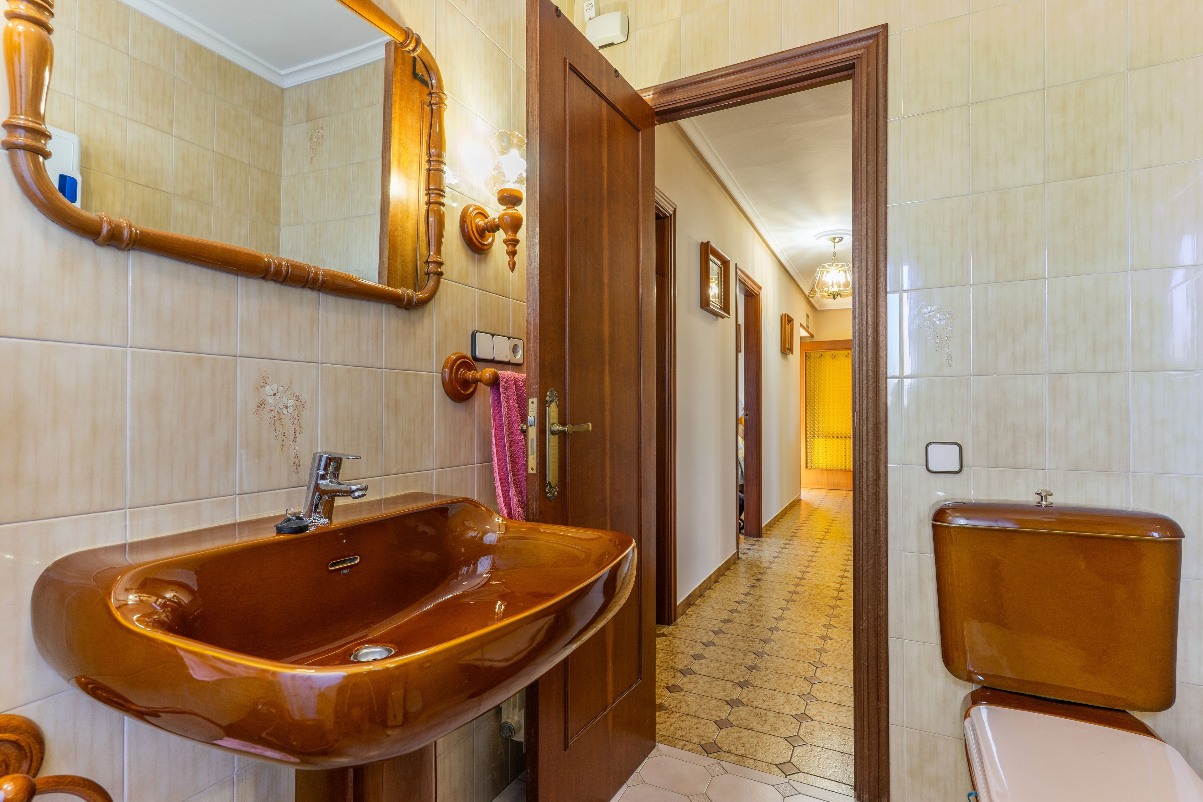 A bathroom with a large wooden vanity, a mirror, and a toilet.