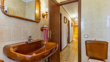 A bathroom with a large wooden vanity, a mirror, and a toilet.