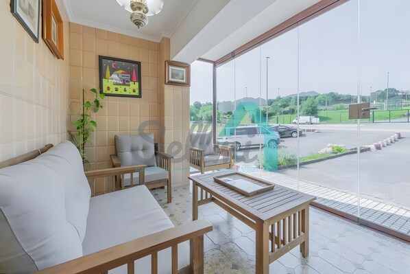 A hotel room with a large window, a sofa, a chair, and a small table.