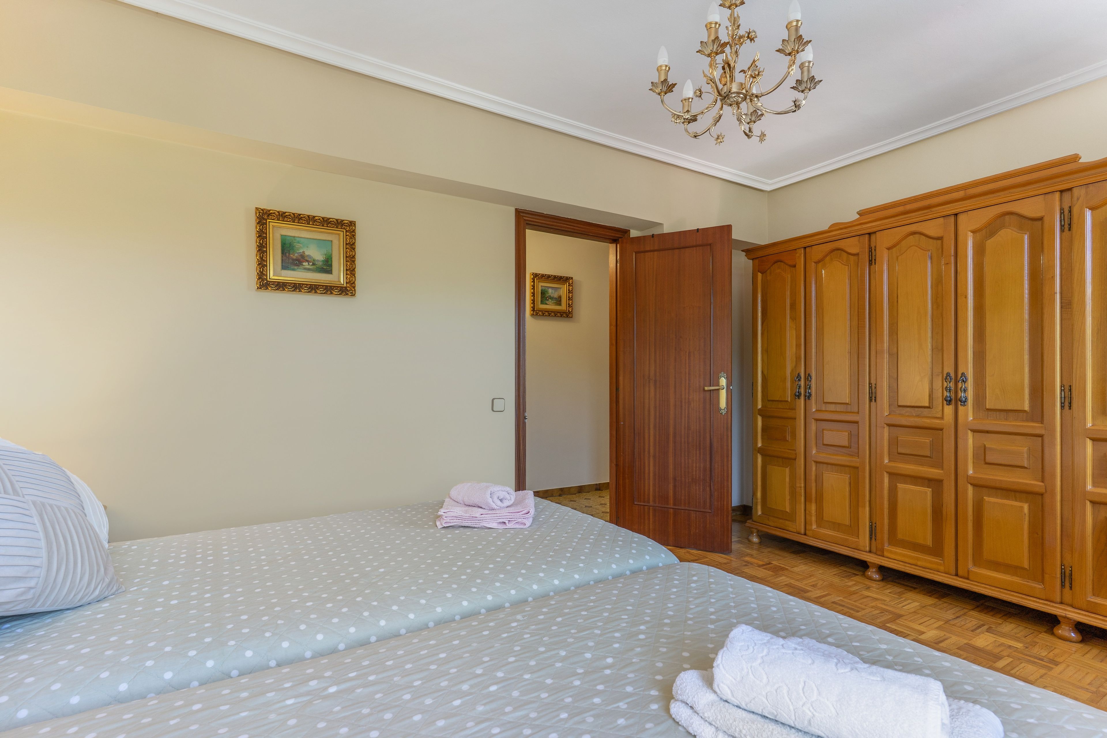 Quarto com cama, guarda-roupa e lustre.
