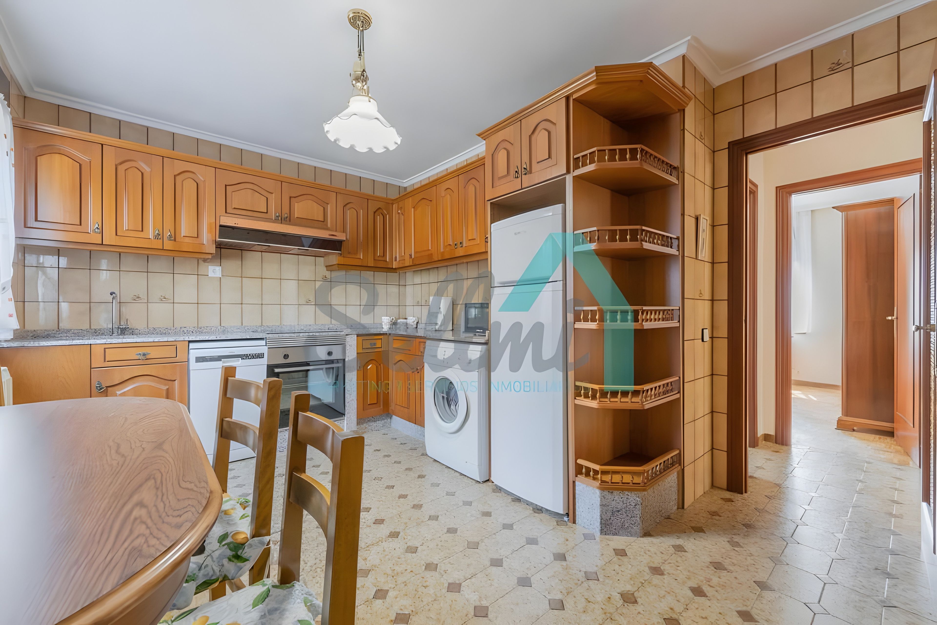 Una cocina con armarios de madera, lavadora y comedor con mesa y sillas.