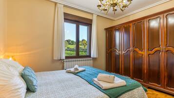 Un dormitorio con una cama grande, un armario, una ventana con vistas y una araña.
