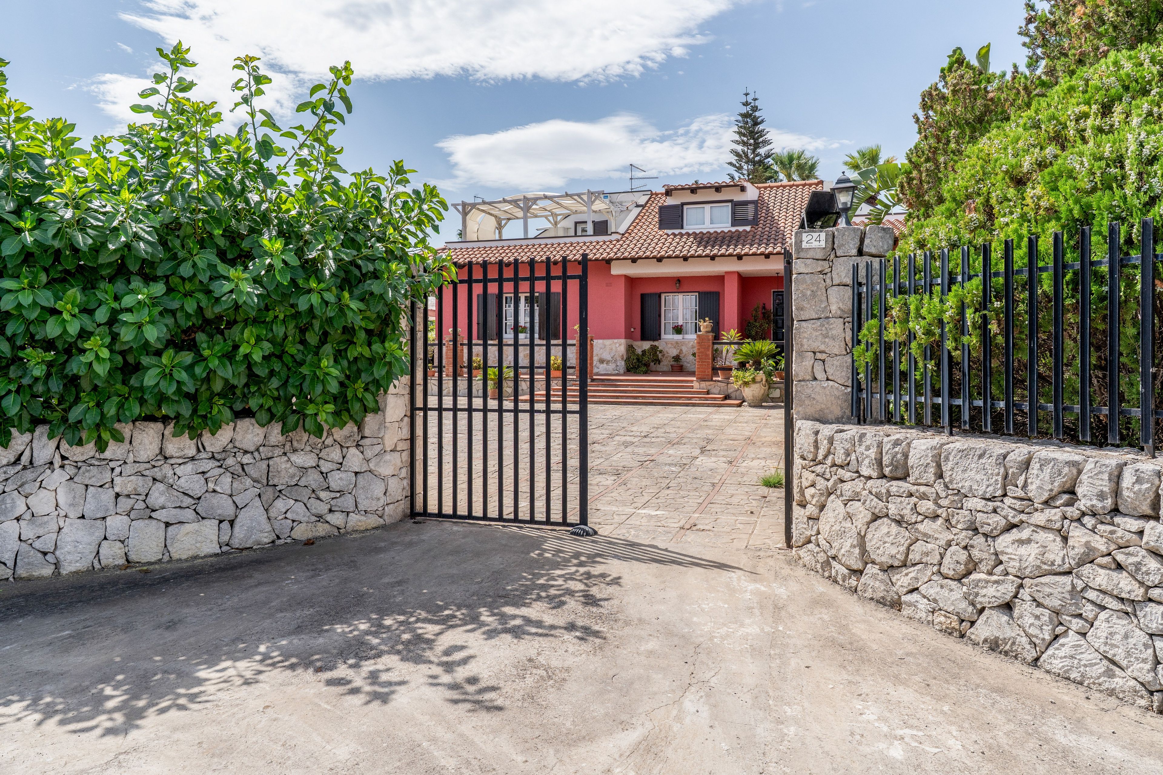 Una entrada protegida con un muro de piedra y una reja de metal.