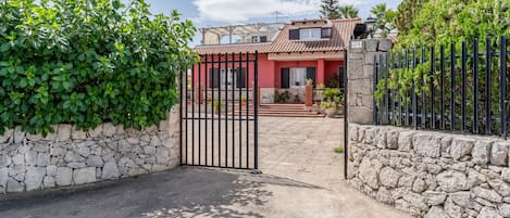 Una entrada protegida con un muro de piedra y una reja de metal.