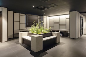 A modern interior with a central seating area, recessed lighting, and a window with blinds.