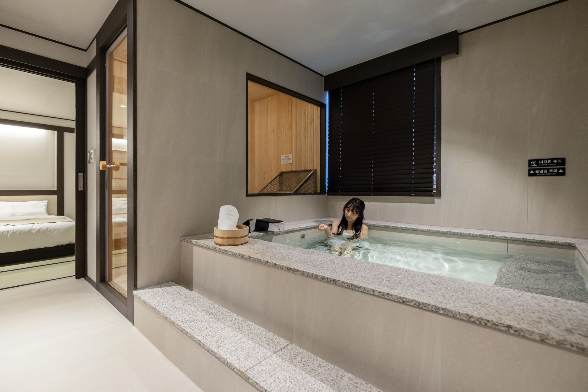 Un baño moderno con una bañera, un banco de madera y un perchero para toallas.