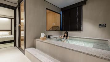 Un baño moderno con una bañera, un banco de madera y un perchero para toallas.