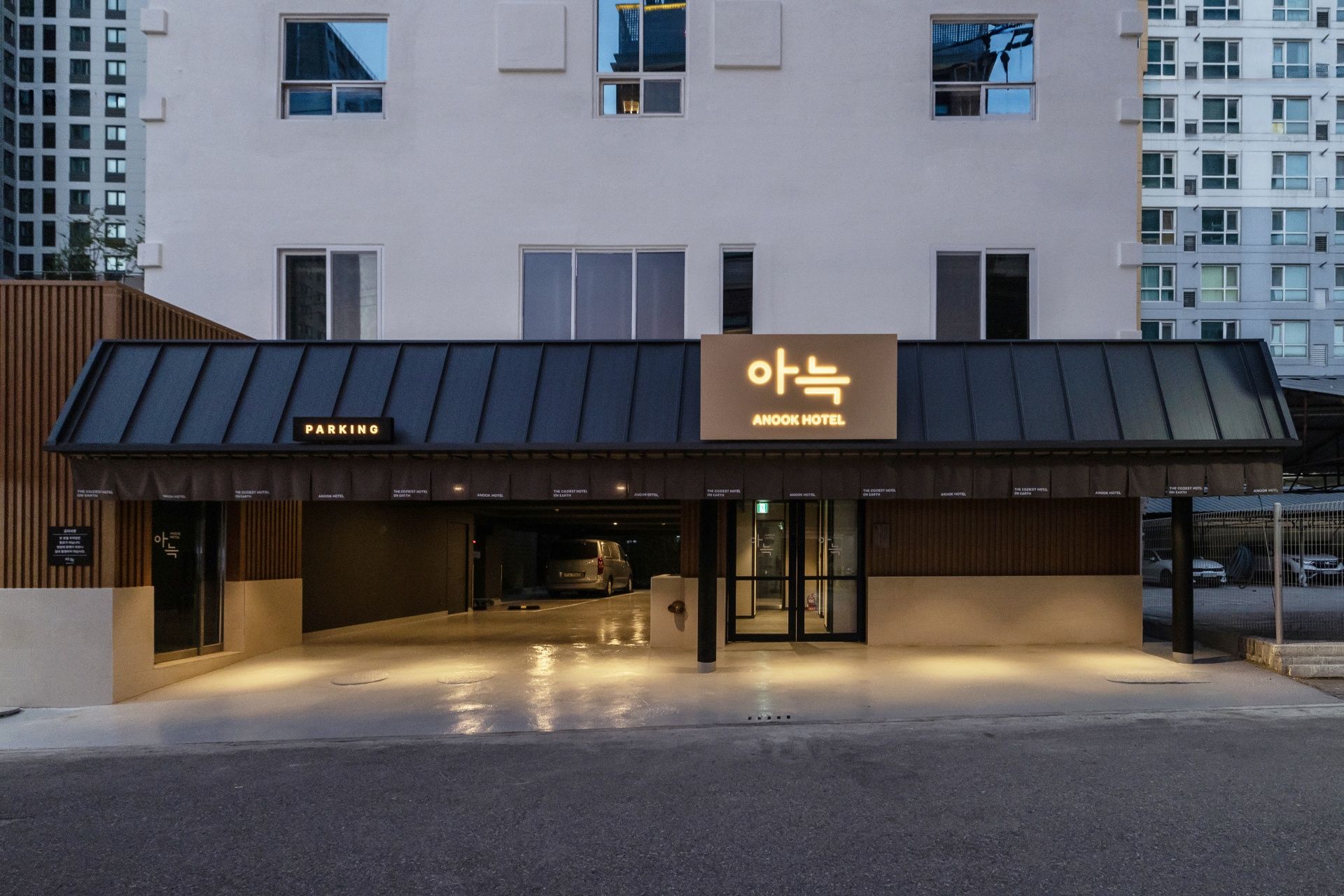 A hotel entrance with a sign for 'AnooK Hotel' and a 'Parking' sign.