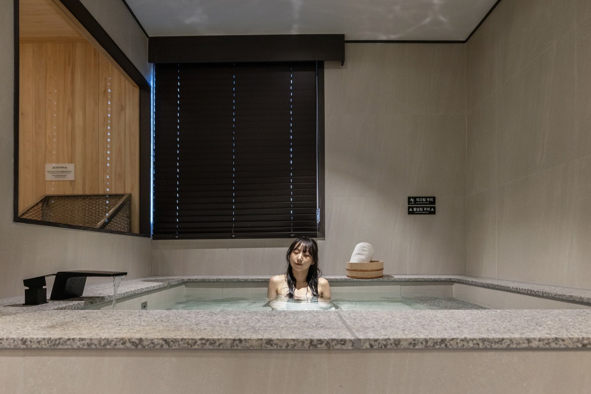 Zona de spa con jacuzzi, paneles de madera y señales de precaución.