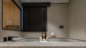 Zona de spa con jacuzzi, paneles de madera y señales de precaución.