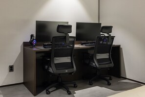 Un espacio de oficina moderno con dos escritorios, cada uno con monitor de computadora, teclado y auriculares.