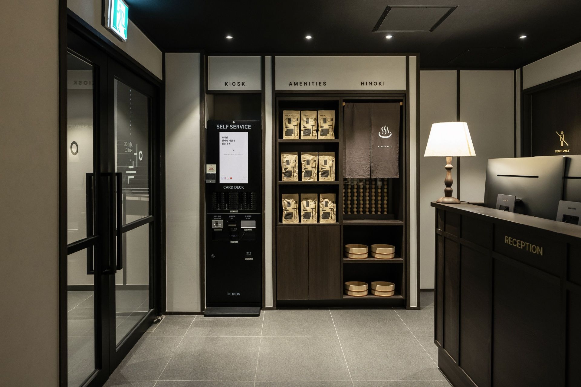 A hotel reception area with a card deck, self-service kiosk, and reception desk.