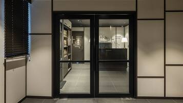 Entrada de un hotel con mostrador de recepción y puerta de vidrio.