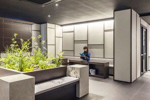 A modern reception area with a seating area, a person reading a book, and a plant arrangement. - ANOOK HOTEL HWAJUNG GWANGJU TERMINAL (Gwangju)