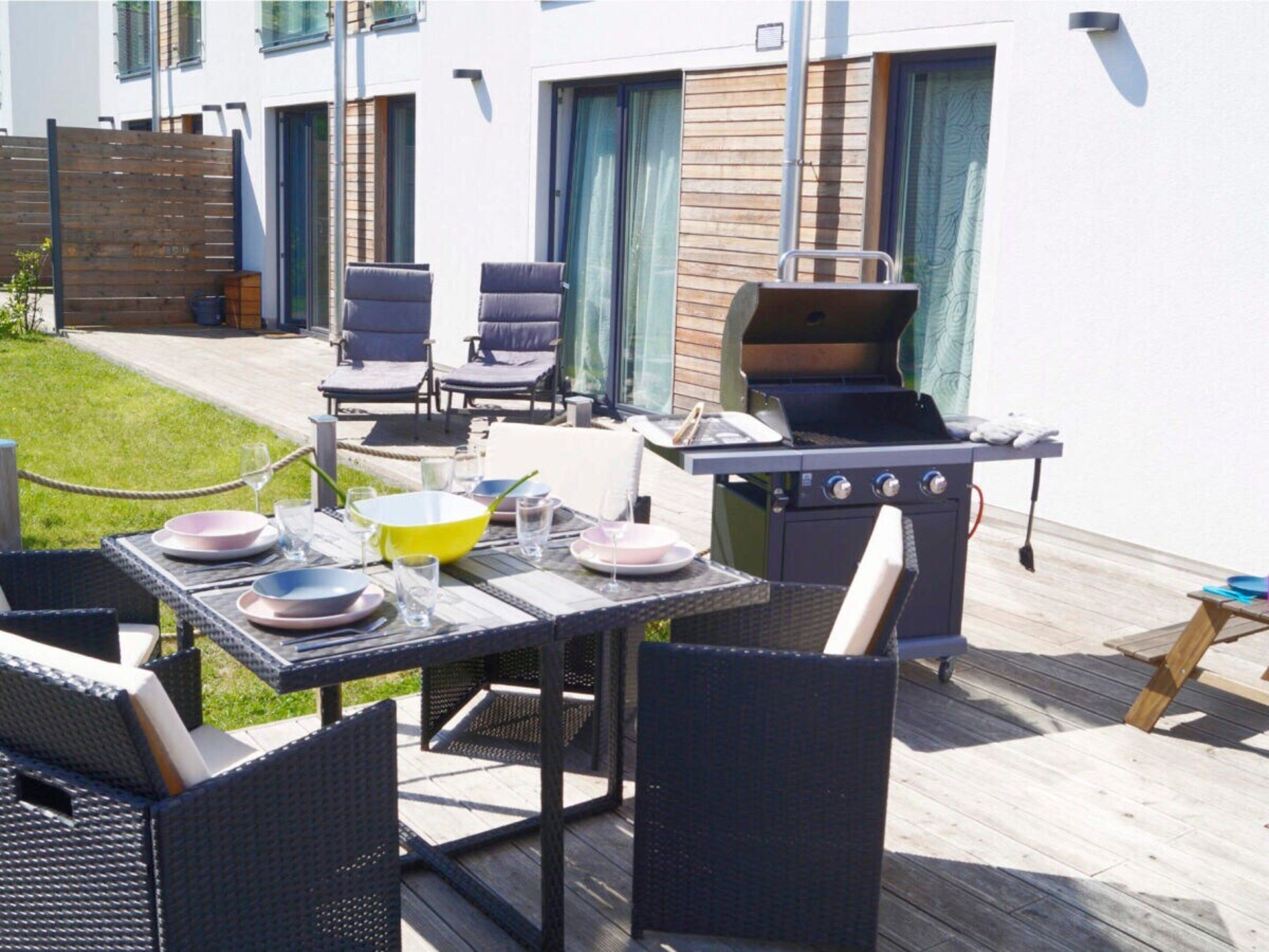 An outdoor patio with a grill, dining table, and chairs.