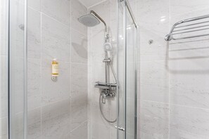 A glass-enclosed shower with a handheld showerhead and a wall-mounted faucet. - GuestReady - Cozy Retreat in Porto Center (Porto)