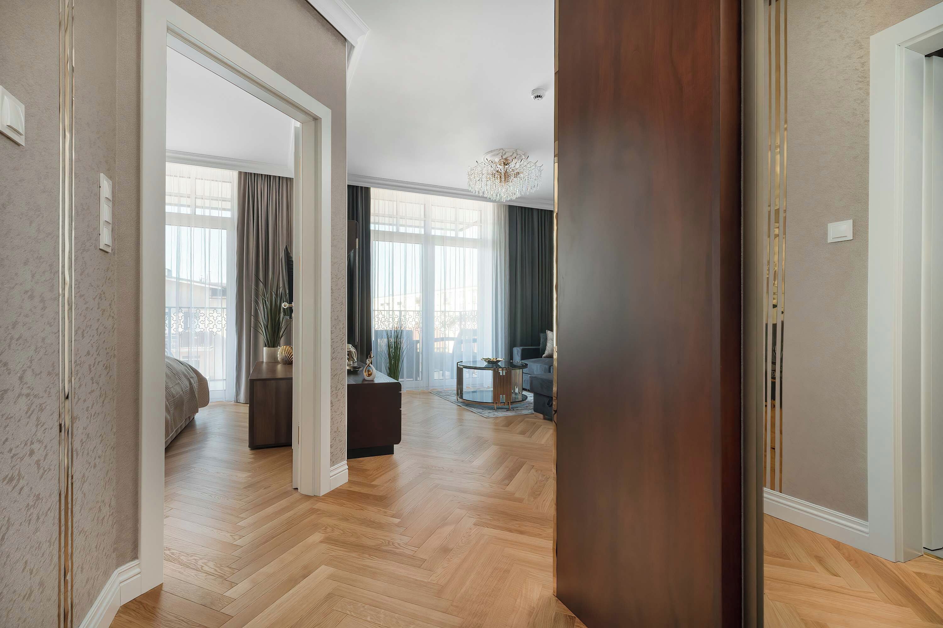 Een ruime woonkamer met een groot raam, een kroonluchter en een bank.